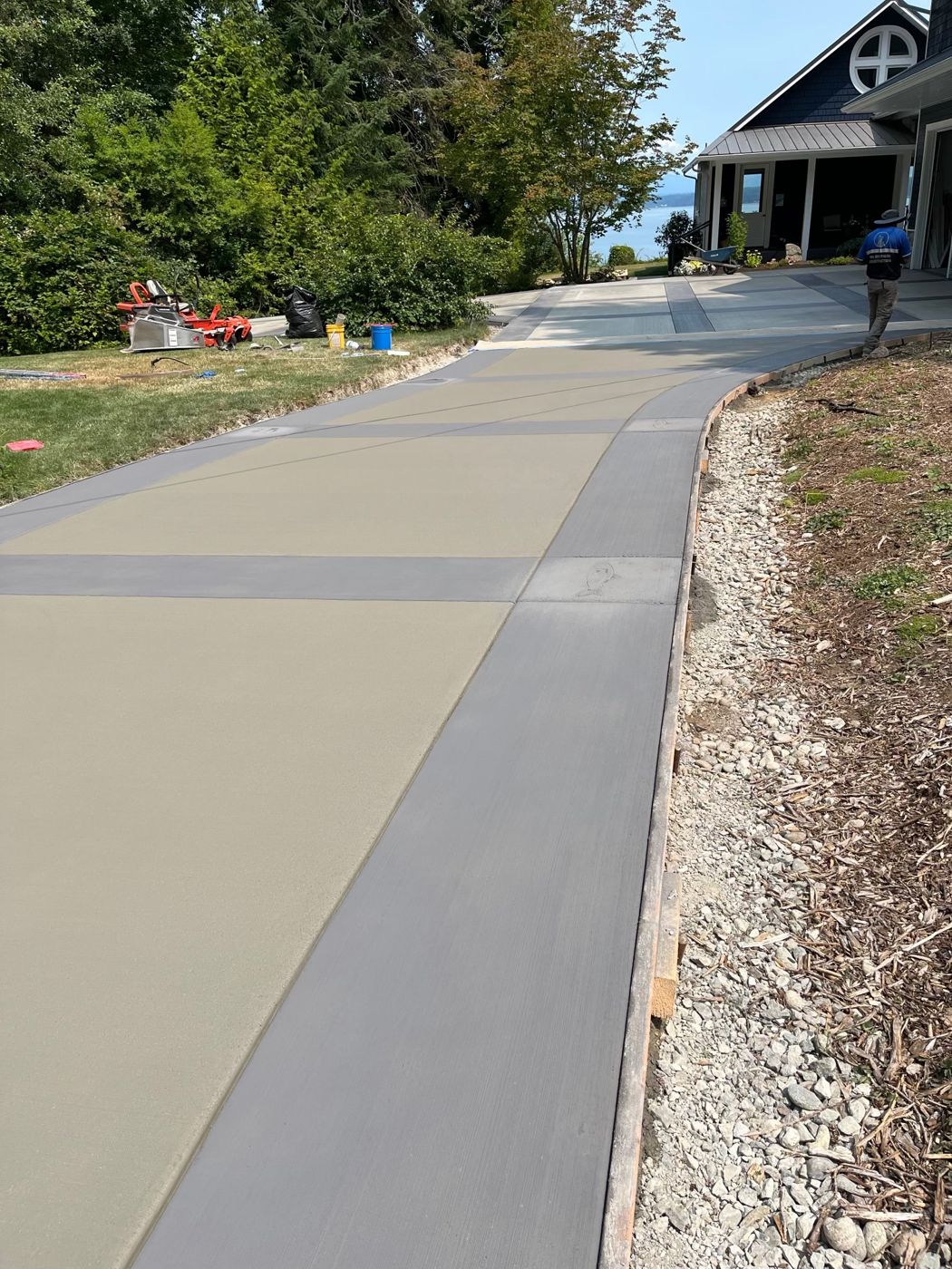 Long concrete driveway with darker smooth-finish bands framing broom-finish panels