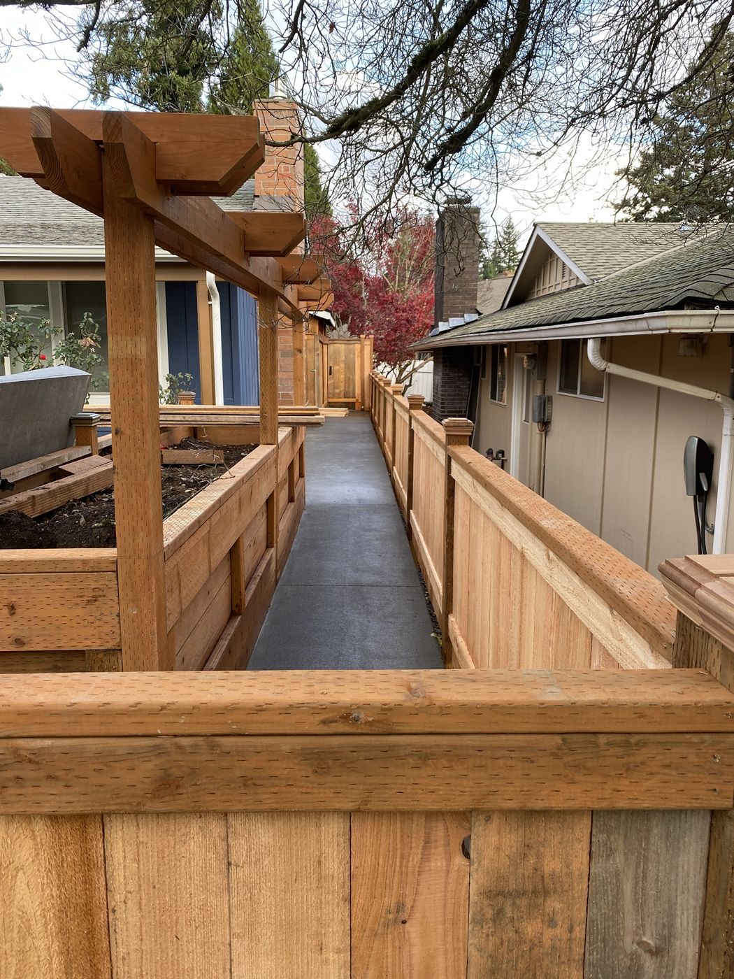 New cedar fence, pergola and raised planter boxes along a concrete side path
