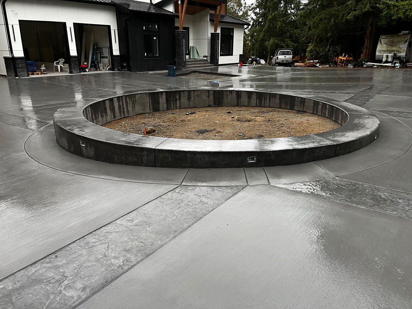 Concrete courtyard driveway with stamped bands and a circular raised planter in front of a modern home