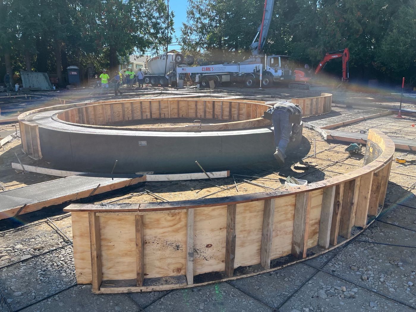 Crew forming curved concrete planter walls, with a pump truck and mixer behind