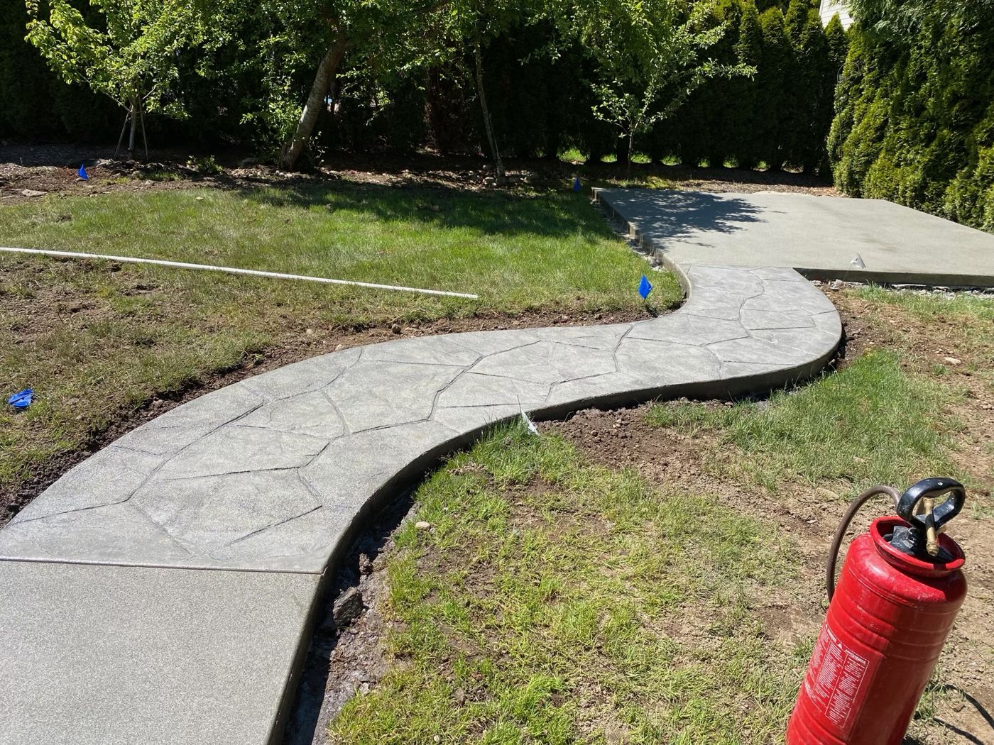 Stamped flagstone concrete path curving across a lawn to connect two patio slabs